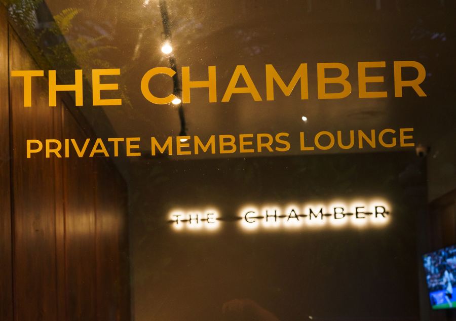 Gold lettering on glass reading 'The Chamber – Private Members Lounge'